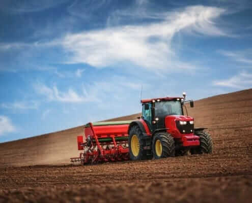 Red tractor ploughing field